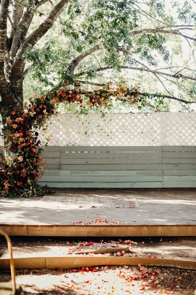 austin wedding venue with gorgeous fall florals on a tree branch with colorful palette and fallen leaves, fall wedding planning, fall color palette, texas hill country wedding, dripping springs wedding