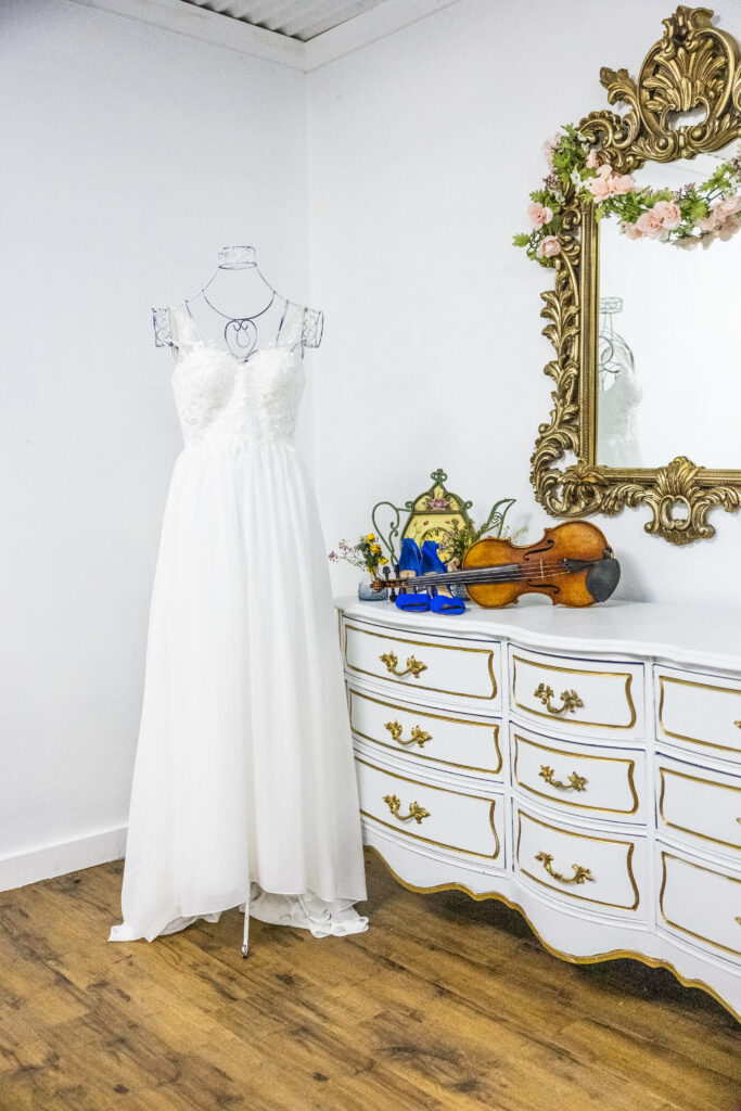 Wedding dress with violin and blue wedding shoes in the Tea Rose Room, Austin Texas wedding venue. Microweddings Austin Texas, Elopements Austin Texas, Weddings Dripping Springs Texas, Microweddings Dripping Springs Texas, Elopements Dripping Springs Texas,  Wedding Shower Austin, Bridal Shower Austin, Wedding Shower Dripping Springs, Bridal Shower Dripping Springs,