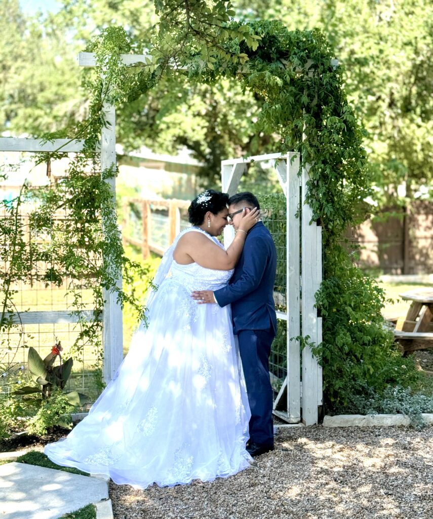 Chapel Dulcinea wedding reception held at Rose Haven Event Venue, Couple pictured under the rose arbor, wedding dress, groom, bride, austin bride, austin wedding venue, austin wedding reception venue, cheap wedding reception venue