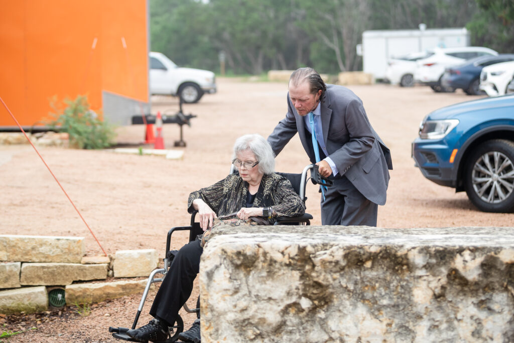 Man helping an elderly woman in a wheelchair at Chapel Dulcinea Austin Wedding Chapel, Free Wedding Chapel, Texas Hill Country Wedding Chapel, Austin Wedding Venue, Austin Bride, Austin wedding reception, Hill Country chapel, Hill Country wedding venue, Dripping Springs Wedding Venue, handicapped friendly, disabled, elderly guests